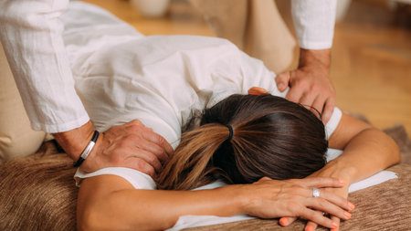 mujer tumbada recibe shiatsu de dos personas